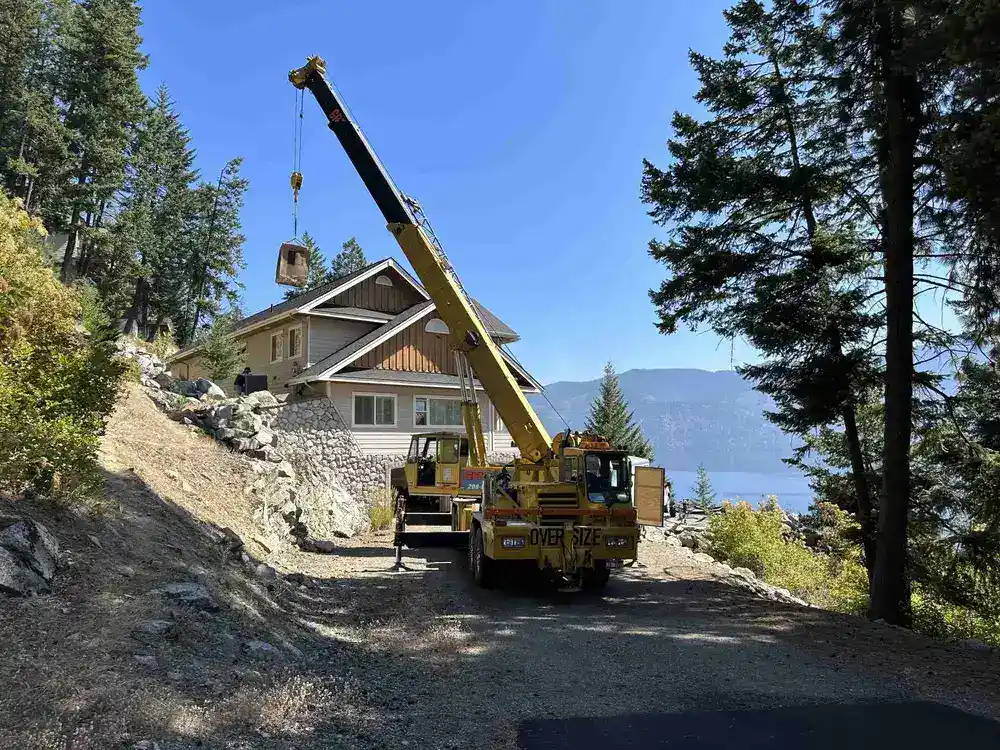 Crane parked in driveway of house on hill