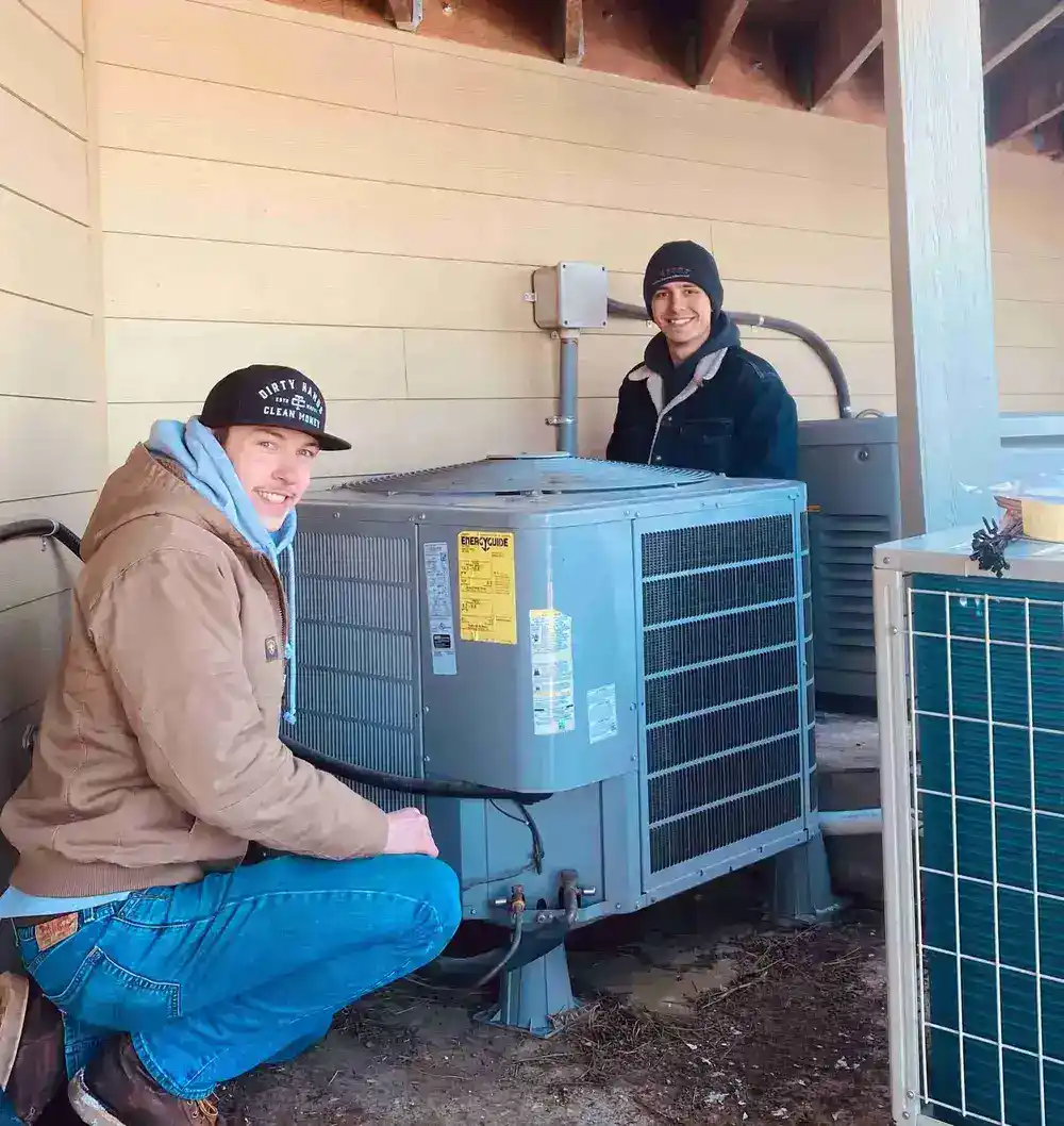 Two smiling technicians working on HVAC unit