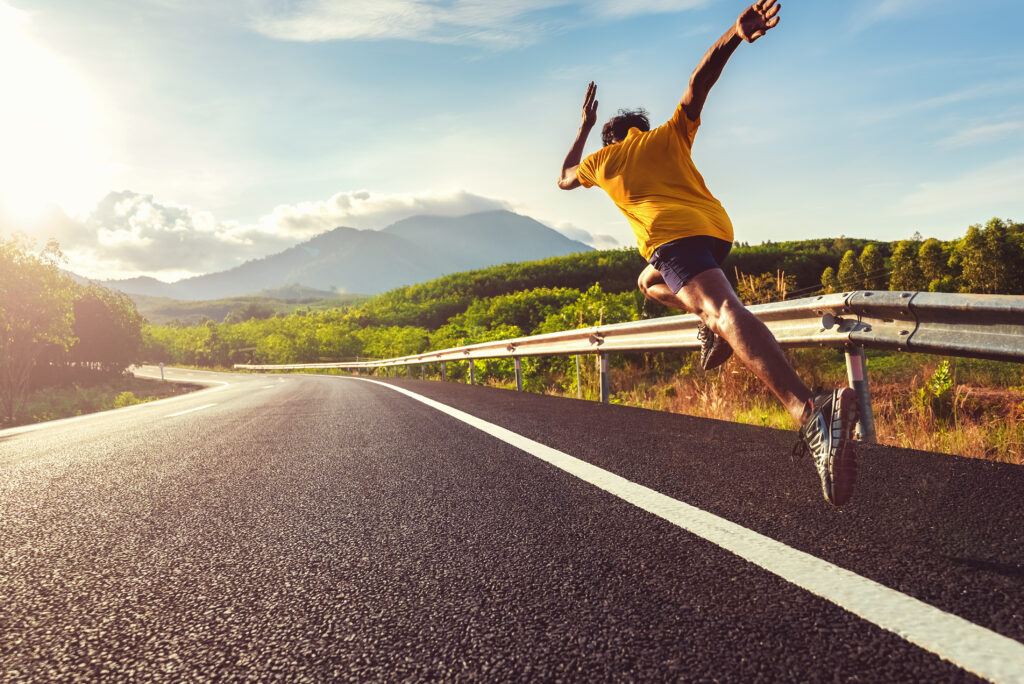 A picture of a man in full running gallop on a roadside. 